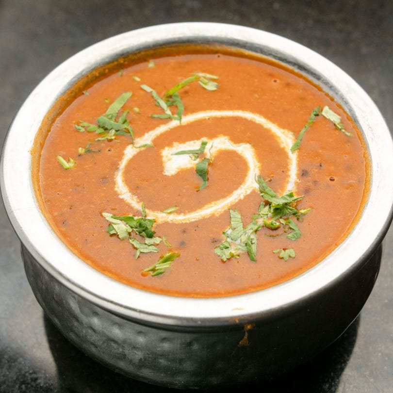 A bowl of The Kurrywala Co.'s Indian dal makhani, garnished with cream swirls and fresh cilantro.